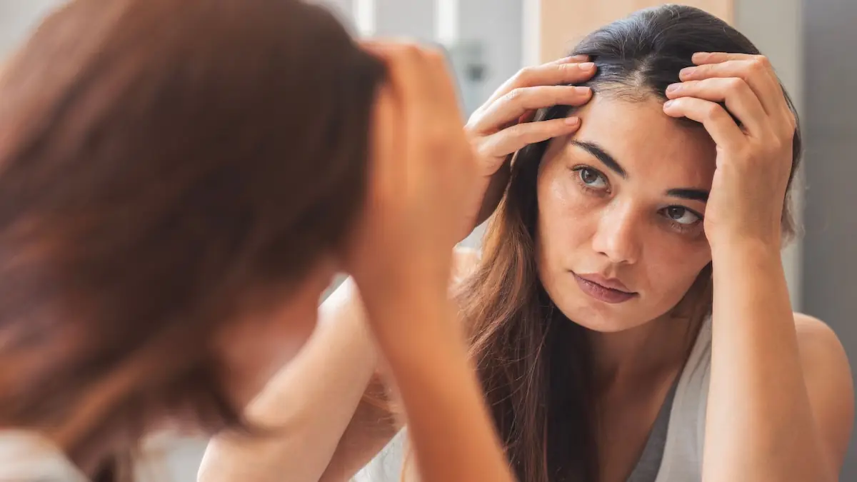 woman looking at her hair roots in the mirror